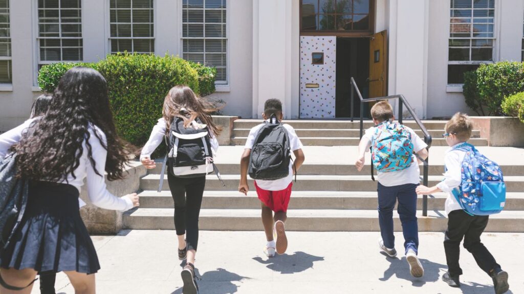 Students with backpacks running toward a school entrance, representing the strong public and private school options in Temecula, California.