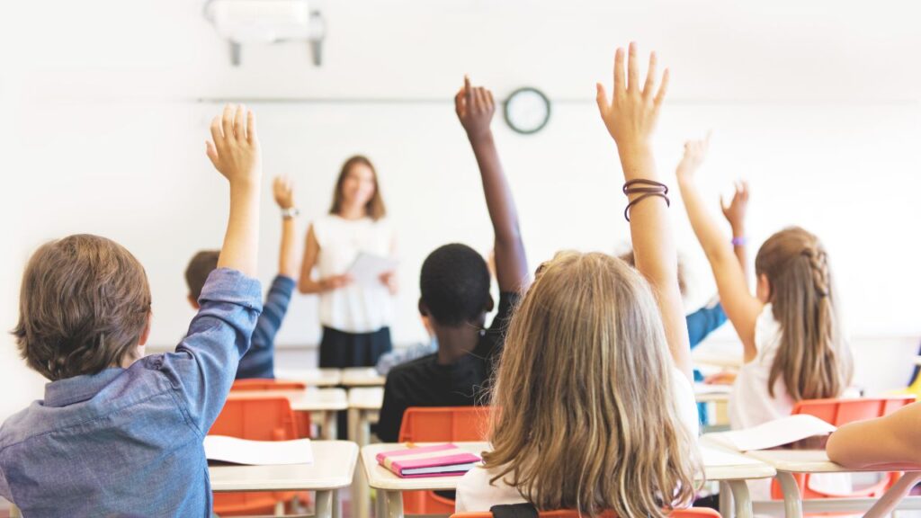 "Students raising their hands in a bright classroom, symbolizing the strong academic reputation of Murrieta's public and charter schools."